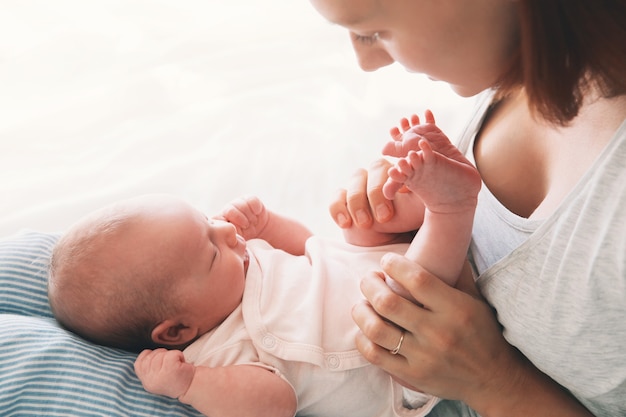 Schöne junge Mutter, die ihr neugeborenes Baby küsst Schlafendes Baby in den Händen seiner liebevollen Mutter