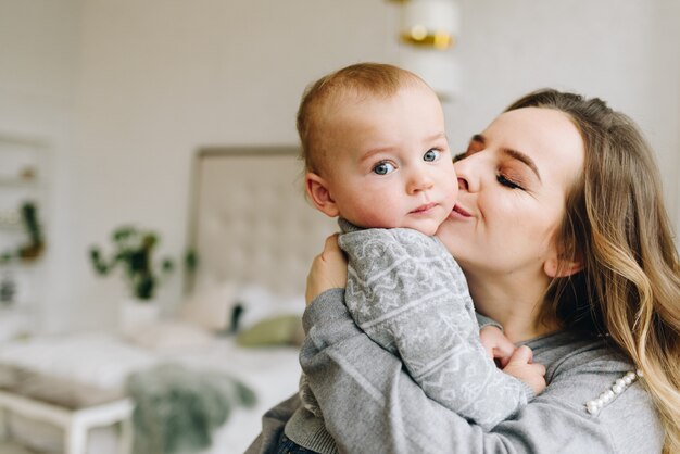 Schöne junge Mutter, die ihren süßen Sohn küsst