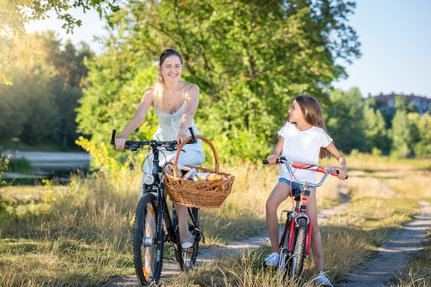 Schöne junge Mutter, die mit Tochter zum Picknick reitet