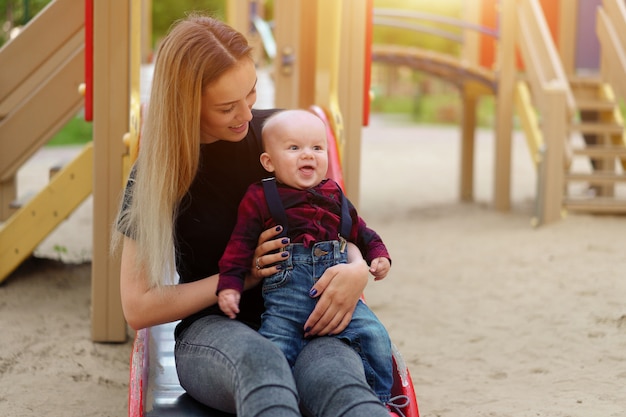 Schöne junge Mutter geht mit ihrem kleinen Sohn in einem Sommerpark