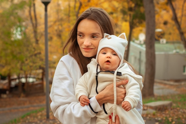 Schöne junge Mutter mit Baby im Herbst