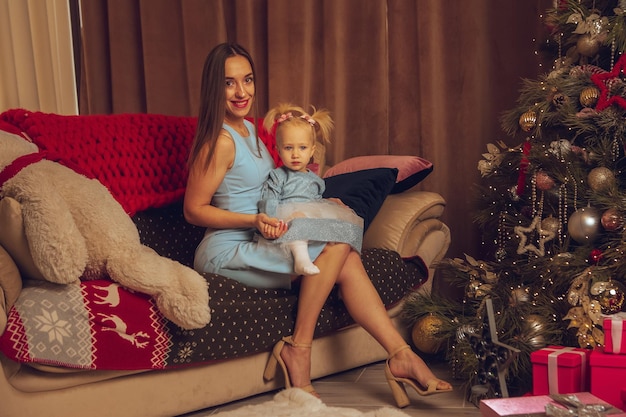 Schöne junge Mutter mit kleinem Baby feiern Weihnachten und Neujahr