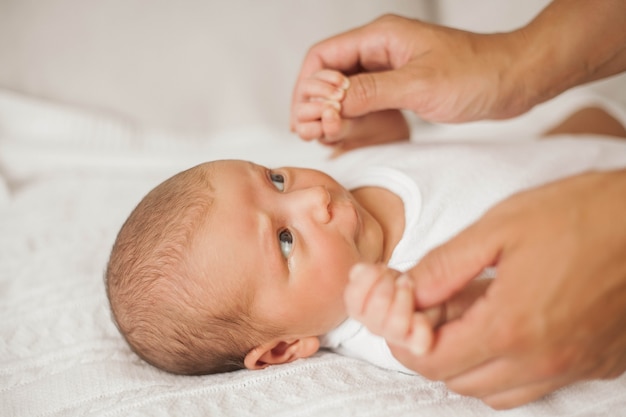 Schöne junge Mutter spielt mit dem Baby im Bett. Mutterschaft.