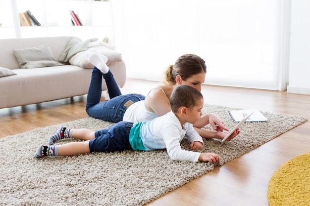 Schöne junge Mutter und ihr Sohn mit digitalen Tablette zu Hause.