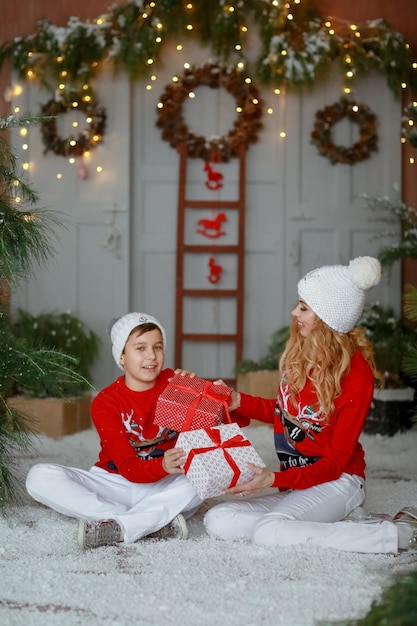 Schöne junge Mutter und Sohn in einem Weihnachtszwergkostüm auf dem Hintergrund der Weihnachtsdekoration.