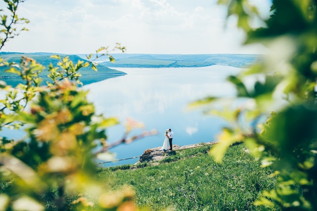 schöne junge Paare, die auf dem Felsen nahe dem See aufwerfen