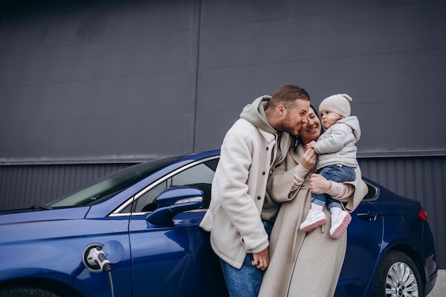 Schöne junge Paare, die Spaß beim Aufladen eines Elektroautos haben