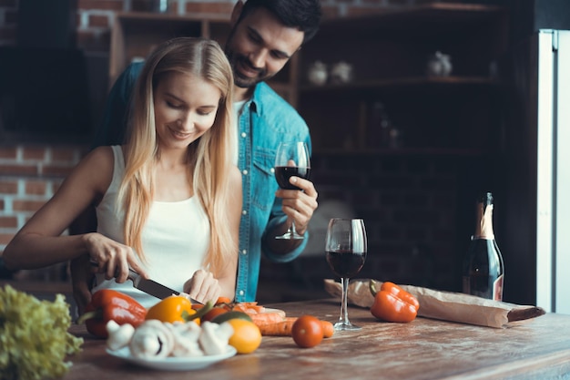Schöne junge Paare, die zusammen eine gesunde Mahlzeit zubereiten, während sie ihre Freizeit zu Hause verbringen