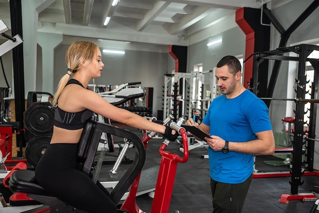 Schöne junge Paare von Mann und Frau trainieren im Fitnessstudio, um sich fit zu halten Das Konzept eines gesunden Lebensstils