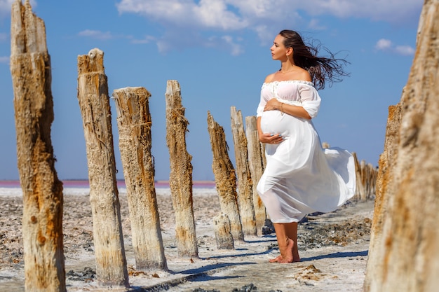 Schöne junge schwangere Frau, die in der Natur auf Salzsee steht.