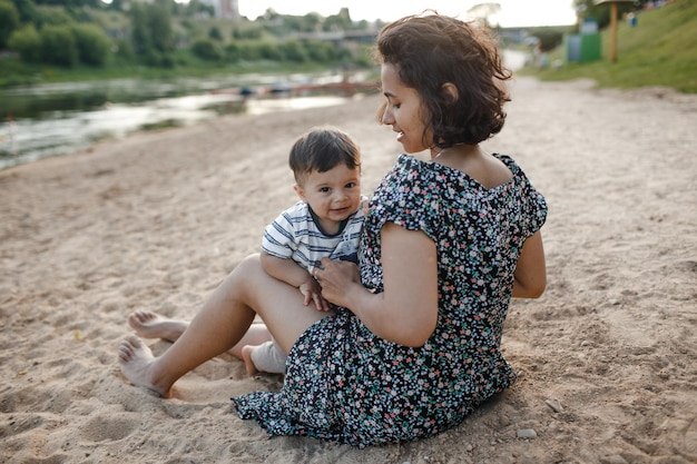 Foto schöne junge schwarze frau spielt mit einem baby am strand in der nähe des flusses