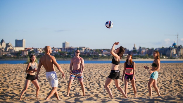 Schöne junge Sportler spielen am Sommerabend Beachvolleyball