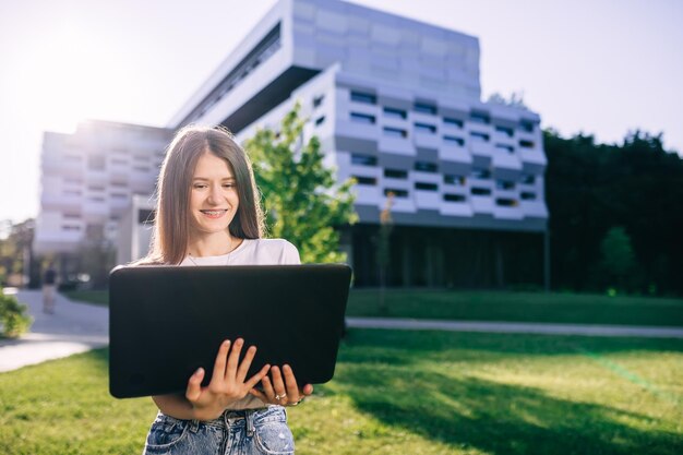 Schöne junge Studentin macht Hausaufgaben am Laptop im Freien