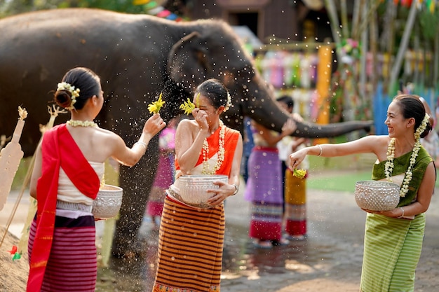 Schöne junge Thai-Dame Ware Thai-Traditionelle Kleidung verwendet Blumen, um Wasser am Songkran-Tag zu besprühen