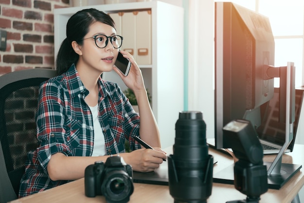 schöne junge weibliche Fotodesign-Redakteurin, die ein Mobiltelefon hält, das mit der Firma spricht und digitale Pad-Technologie verwendet, Stiftzeichnung, Foto retuschieren.