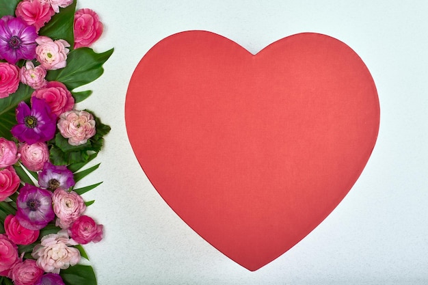 Schöne Karte für den Feiertag der Liebe. Hintergrund zum Valentinstag. Postkarte für Hochzeiten. Rosa Blumen auf weißem Hintergrund und rote Herzen für Text.