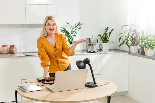 Schöne kaukasische Frau, die an Laptop arbeitet. Küche Hintergrund.