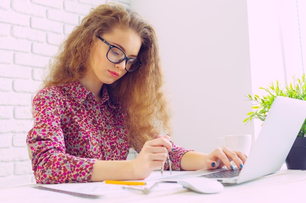 Schöne kaukasische Frau, die an Laptop sitzt und arbeitet