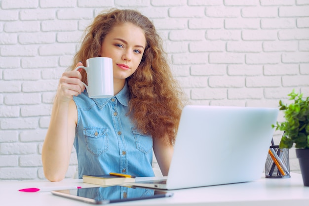 Schöne kaukasische Frau, die an Laptop sitzt und arbeitet