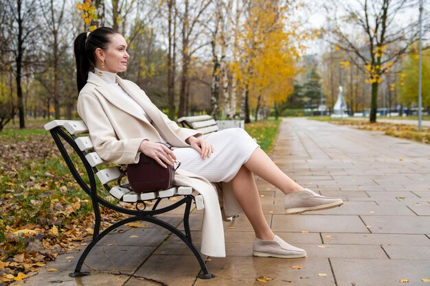Schöne kaukasische Frau, die auf einer Bank im Park sitzt