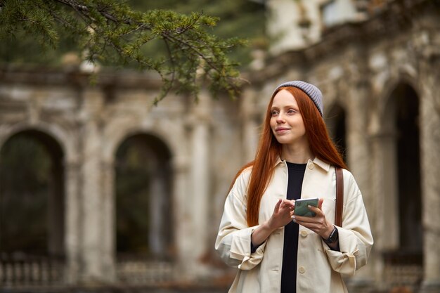 Schöne kaukasische Frau, die morgens an historischen Orten mit Smartphone-Erwachsenenweib...