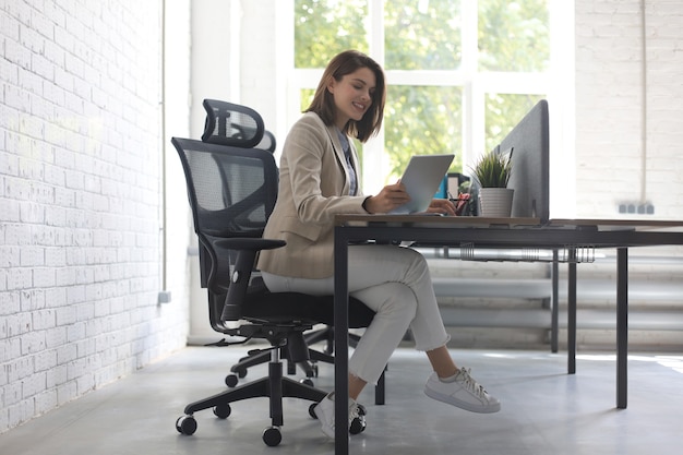 Schöne kaukasische Geschäftsfrau arbeitet mit digitalem Tablet beim Sitzen im Kreativbüro.
