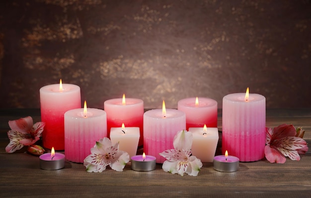 Schöne Kerzen mit Blumen auf dem Tisch auf braunem Hintergrund