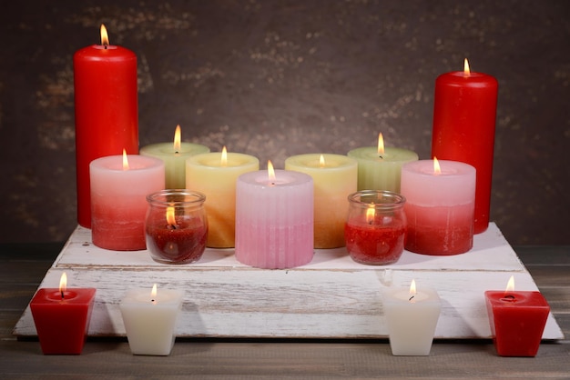 Schöne Kerzen mit Blumen auf dem Tisch auf braunem Hintergrund