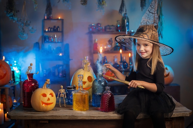 Schöne kleine Hexe mit Halloween-Dekorationen