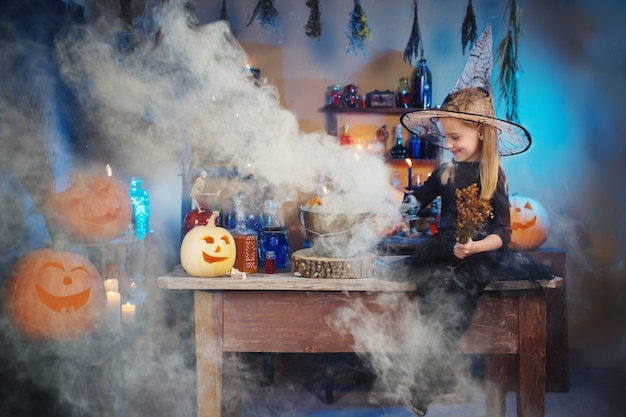 Schöne kleine Hexe mit Halloween-Dekorationen