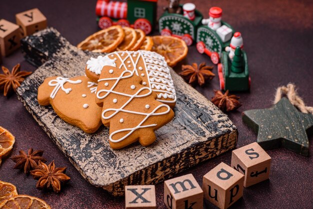 Foto schöne, köstliche, süße weihnachts-gingerbread-kekse auf bronze-hintergrund