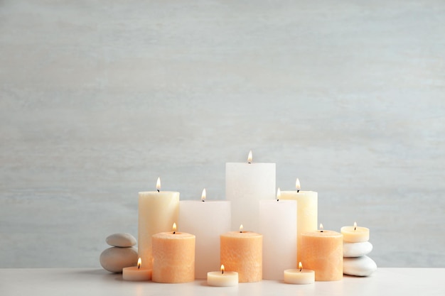 Schöne Komposition mit Kerzen auf dem Tisch vor hellem Hintergrund Platz für Text