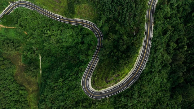 Schöne kurvenstraße auf grünem wald im hintergrund der regenzeit ländliche wege, die städte im norden thailands verbinden