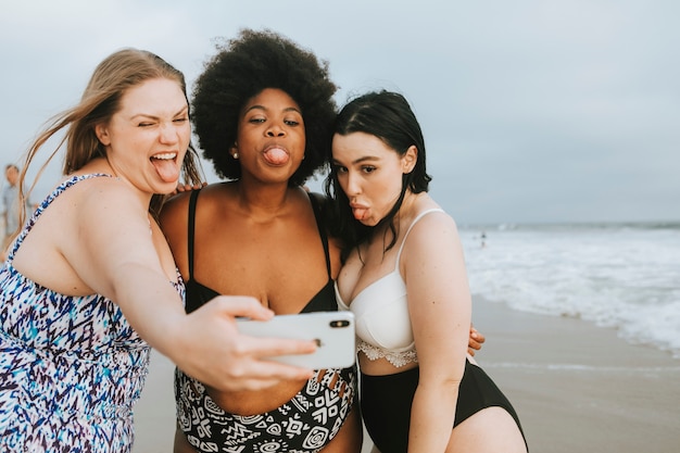 Schöne kurvige Frauen, die ein selfie am Strand nehmen
