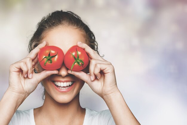 Schöne lachende Frau mit zwei reifen Tomaten