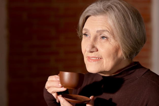 Schöne lächelnde ältere Frau, die Tee trinkt