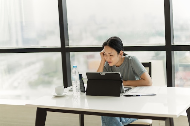 Schöne lächelnde Frau bei einem Videoanruf auf ihrem Tablet während der Arbeit im Büro