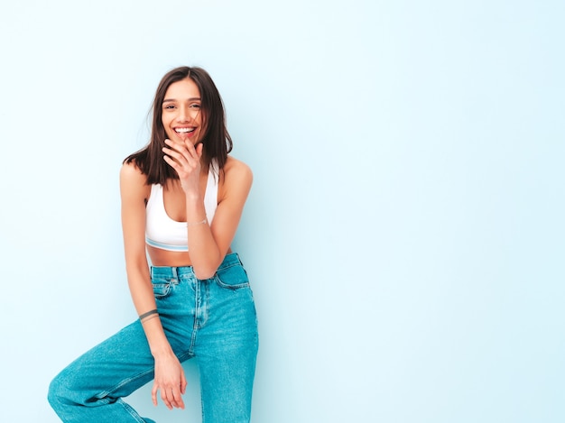 Schöne lächelnde Frau in weißem Jersey-Top-Shirt und Jeans gekleidet