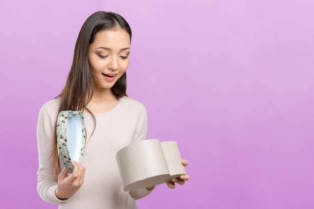 Schöne lächelnde Frau mit dem langen Haar, das Geschenkbox hält