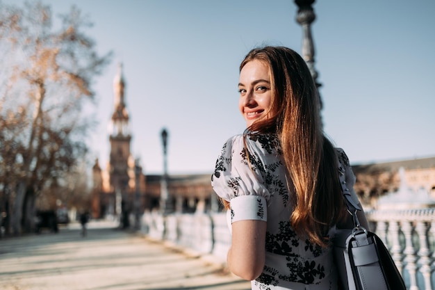 Schöne lächelnde junge Frau, die sich beim Sightseeing in Sevilla, Spanien, der Kamera zuwendet