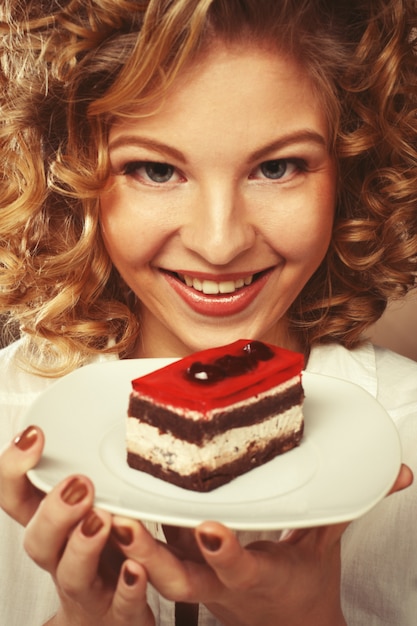 Schöne lächelnde junge Frau mit einem Kuchen