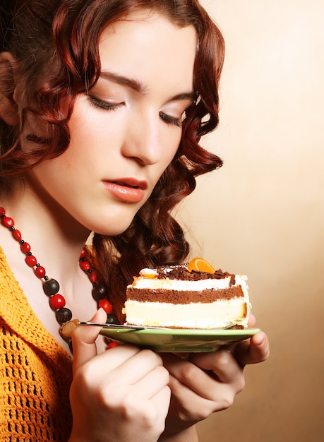 Foto schöne lächelnde junge lockige frau mit einem kuchen