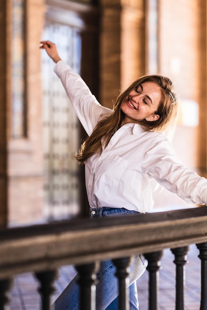 Schöne lächelnde kaukasische Frau, die auf einem Balkon auf der Plaza de Espana in Sevilla tanzt