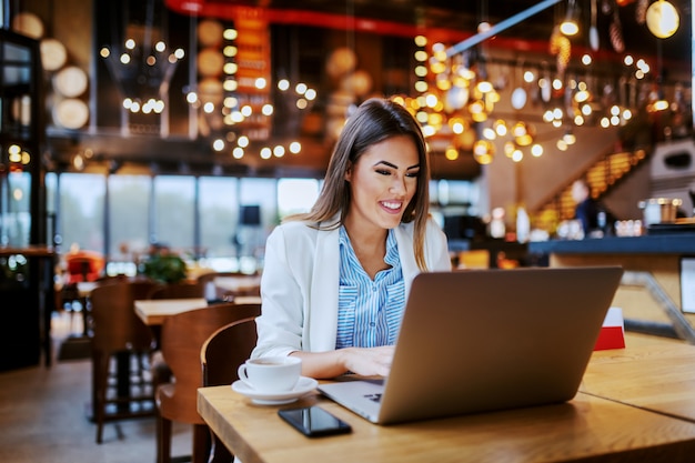 Schöne lächelnde positive modische kaukasische Anwältin, die im Café sitzt