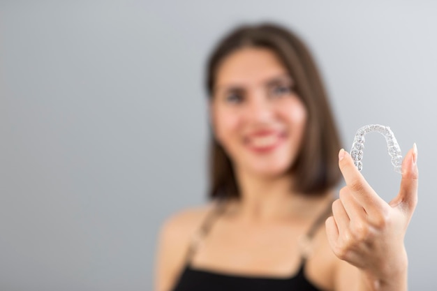 Schöne lächelnde Türkin hält eine Invisalign-Armschiene Isolierte Studioaufnahme mit Kopierraum