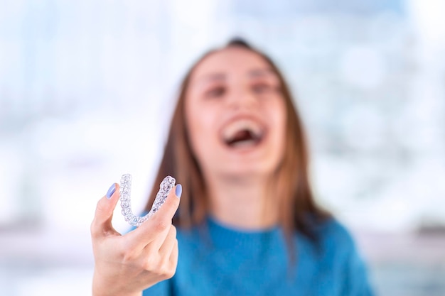 Schöne lächelnde Türkin hält eine Invisalign-Armschiene mit Kopierraum