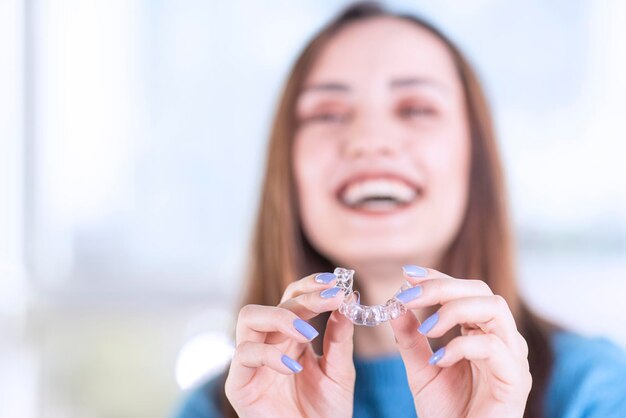 Schöne lächelnde Türkin hält eine Invisalign-Armschiene mit Kopierraum