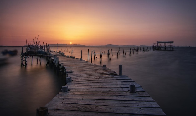 Schöne Landschaft eines hölzernen Docks in einem Hafen in Carrasqueira, Comporta, Portugal bei Sonnenuntergang