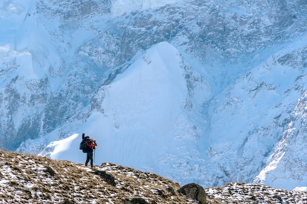 Schöne Landschaft mit Bergen, blauem riesigen Gletscher und Silhouette eines Mannes, der mit einem großen Rucksack und einer Gitarre geht