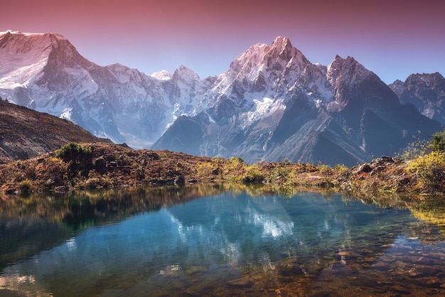 Schöne Landschaft mit hohen Bergen mit schneebedeckten Gipfeln, Himmel spiegelt sich im See. Bergtal mit Spiegelung im Wasser bei Sonnenaufgang. Nepal. Erstaunliche Szene mit Himalaya-Bergen. Natur